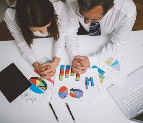 Business professionals reviewing charts and performance data to evaluate results and support decision making Business professionals reviewing charts and performance data to evaluate results and support decision making